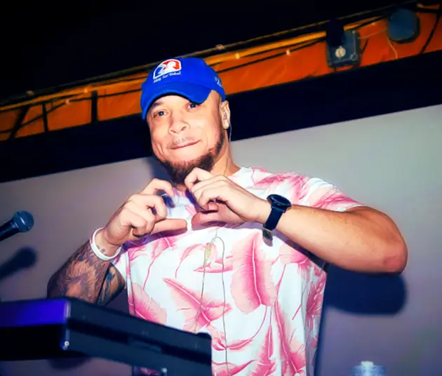 An image of DJ Rojito and he is doing a heart sign with his hands.