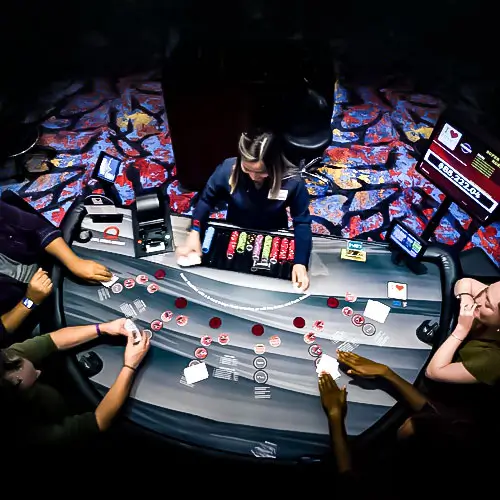 A shot from above of a table games table with a dealer and four players.