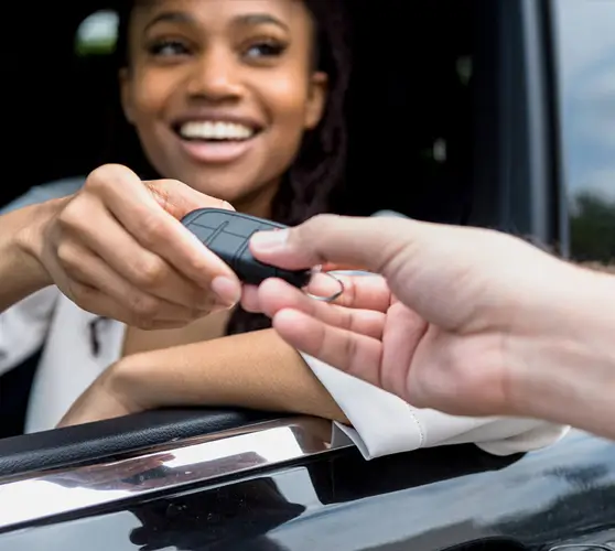 An image of a woman in a car receiving her key from another hand.